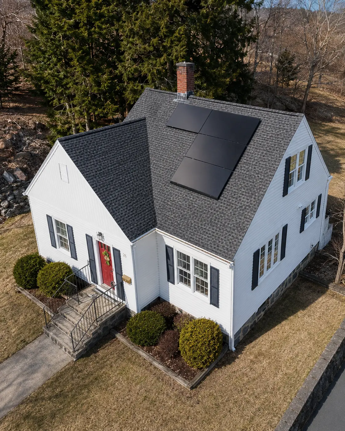 Aerial view of a white home with red door and black solar panels