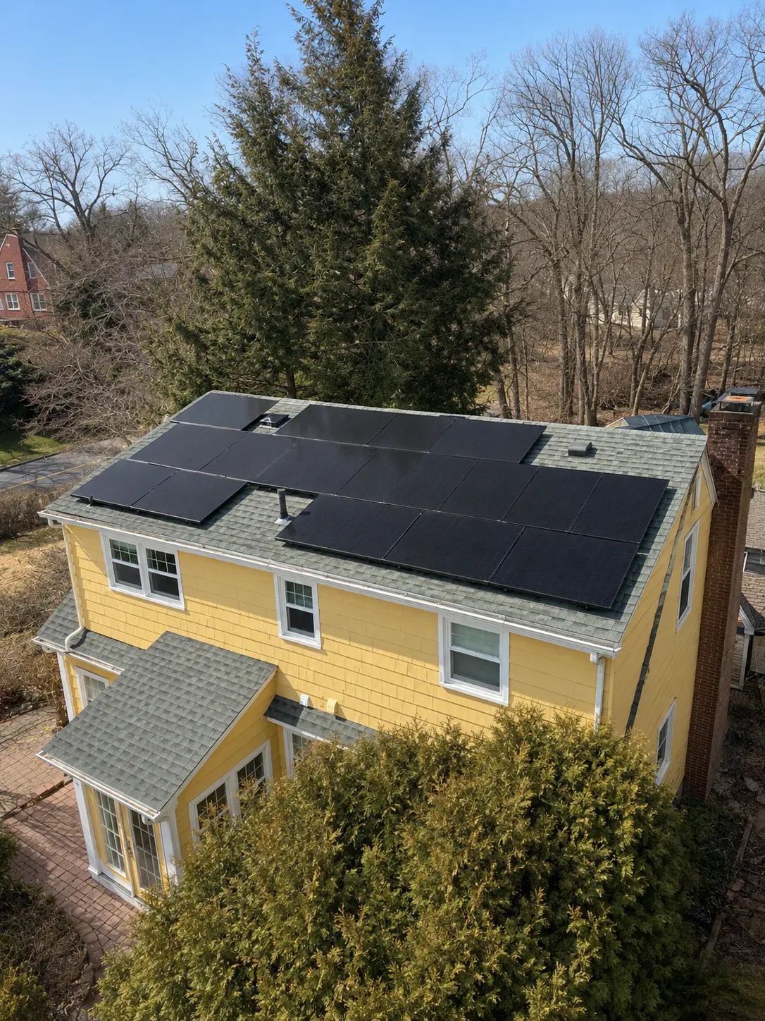 Aerial view of a yellow two-story home with full roof-mounted solar array